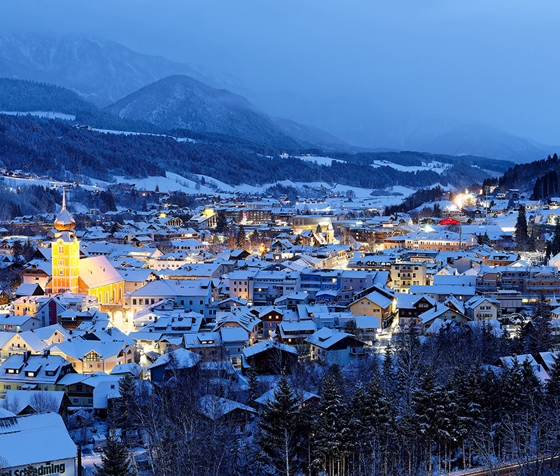Panoramica notturna di città europea con luci invernali e neve leggera