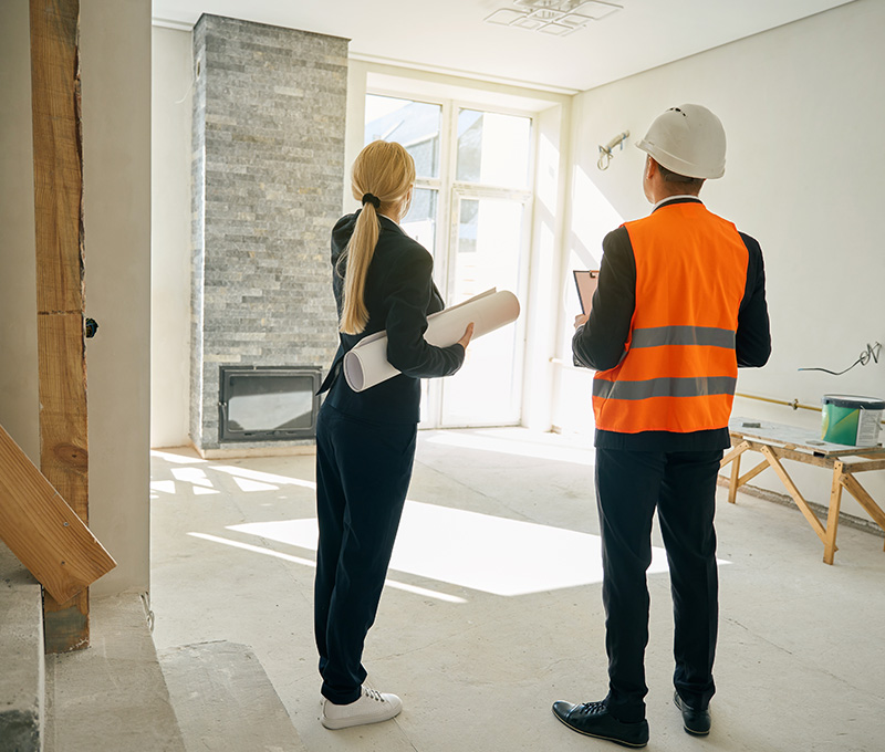 Tecnico e cliente esaminano i lavori di ristrutturazione antisismica di un edificio residenziale.